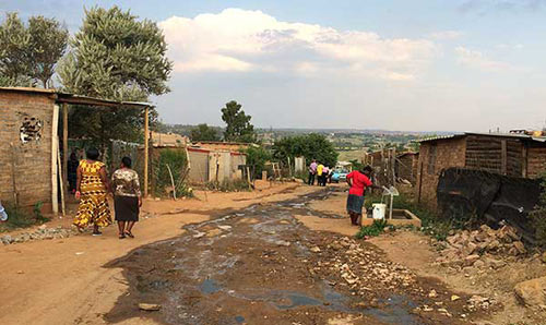 image of unpaved road in South Africa with houses on either side.