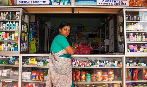 Woman stood in front of a seller's kiosk.