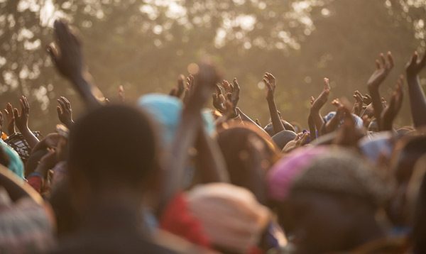 A tightly grouped crowd of people with hands in the air
