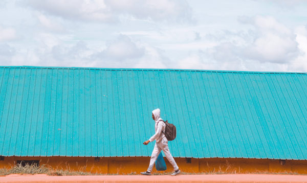 Man in white walks along the road in Kampala, Uganda
