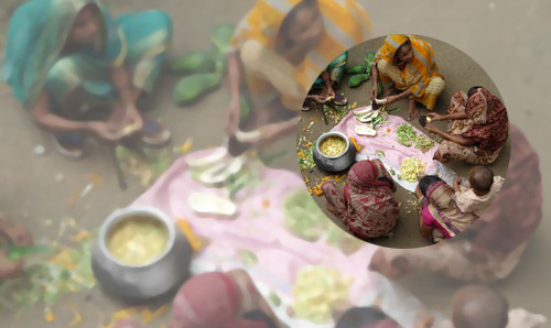 Bangladeshi women sat in a circle on the floor around a pot of food